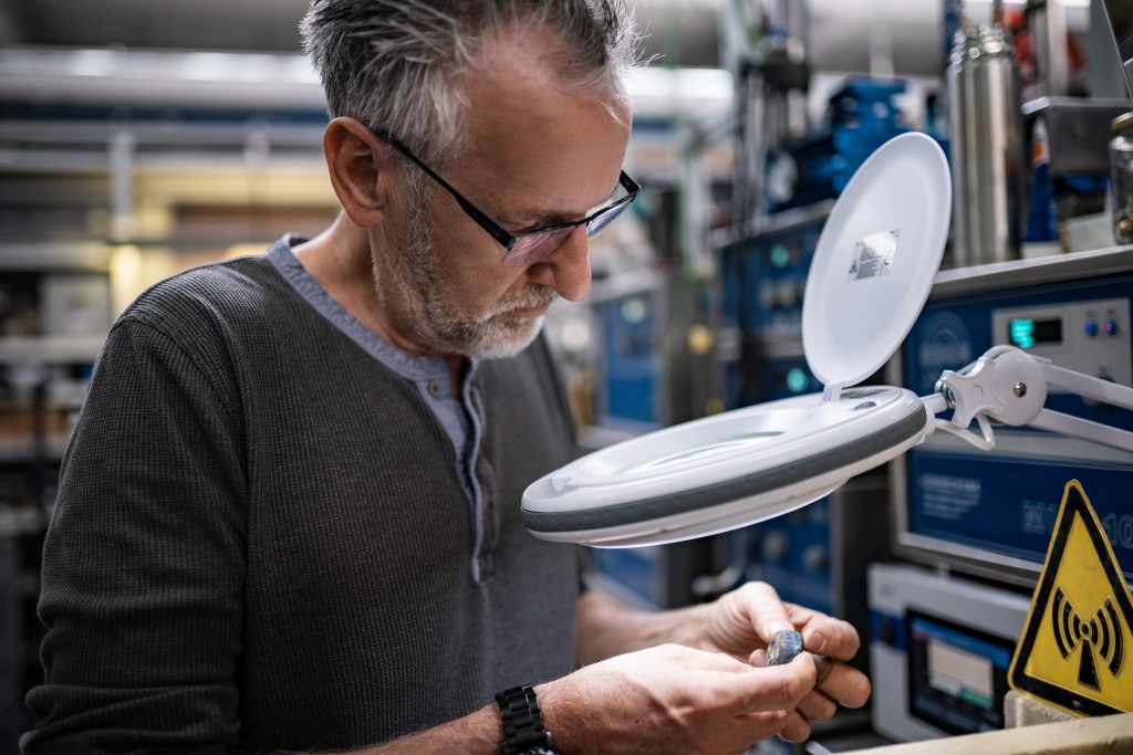 Een ontwikkelaar bekijkt in het laboratorium een werkstuk met een vergrootglas